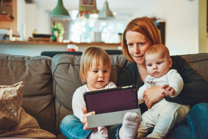 Aikuinen ja kaksi lasta tietokoneen kanssa sohvalla.